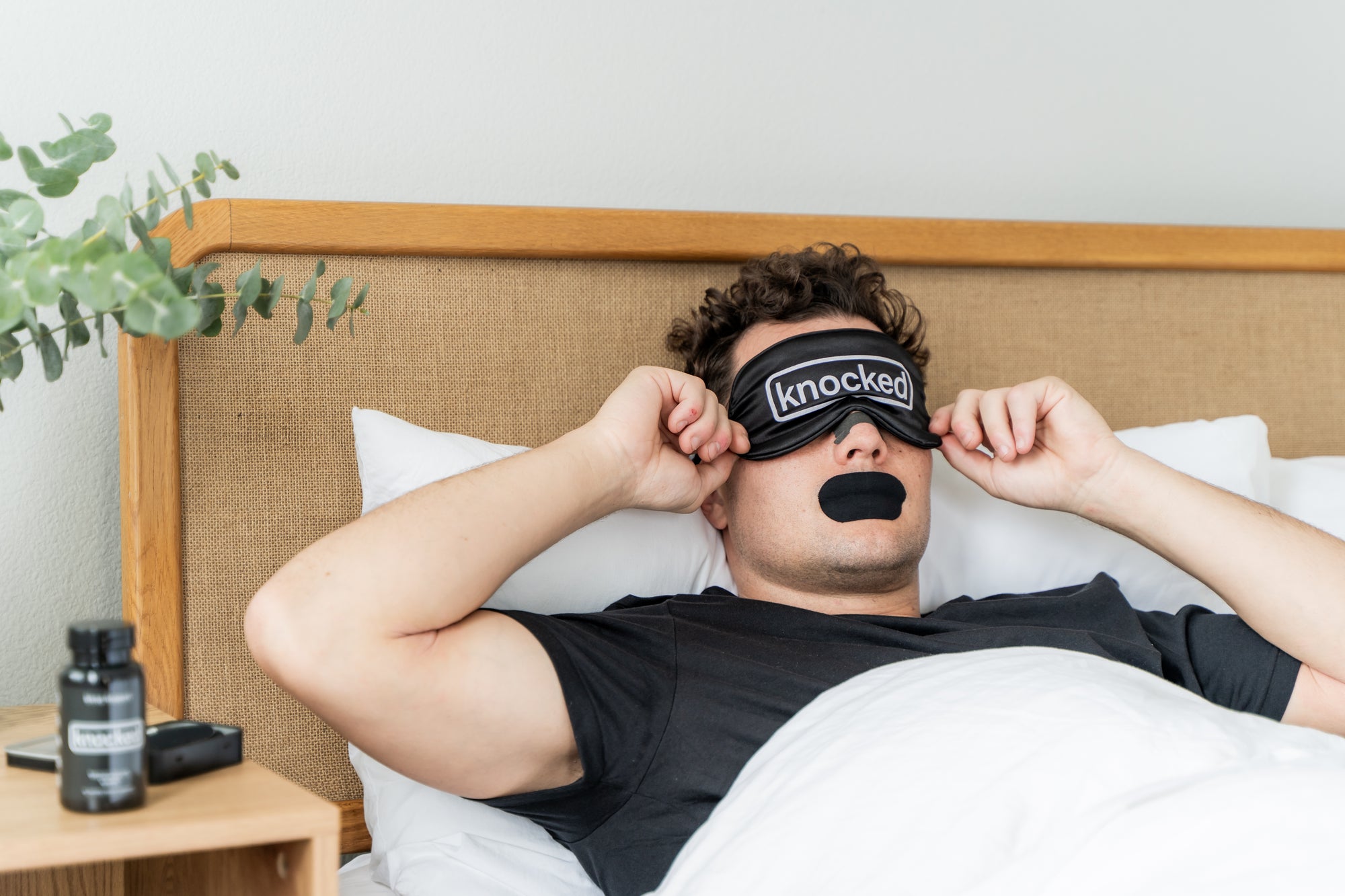 Wearing Knocked Eye Mask, Nose Strips, and Mouth Tape to bed. Supplement Featured on bedside table