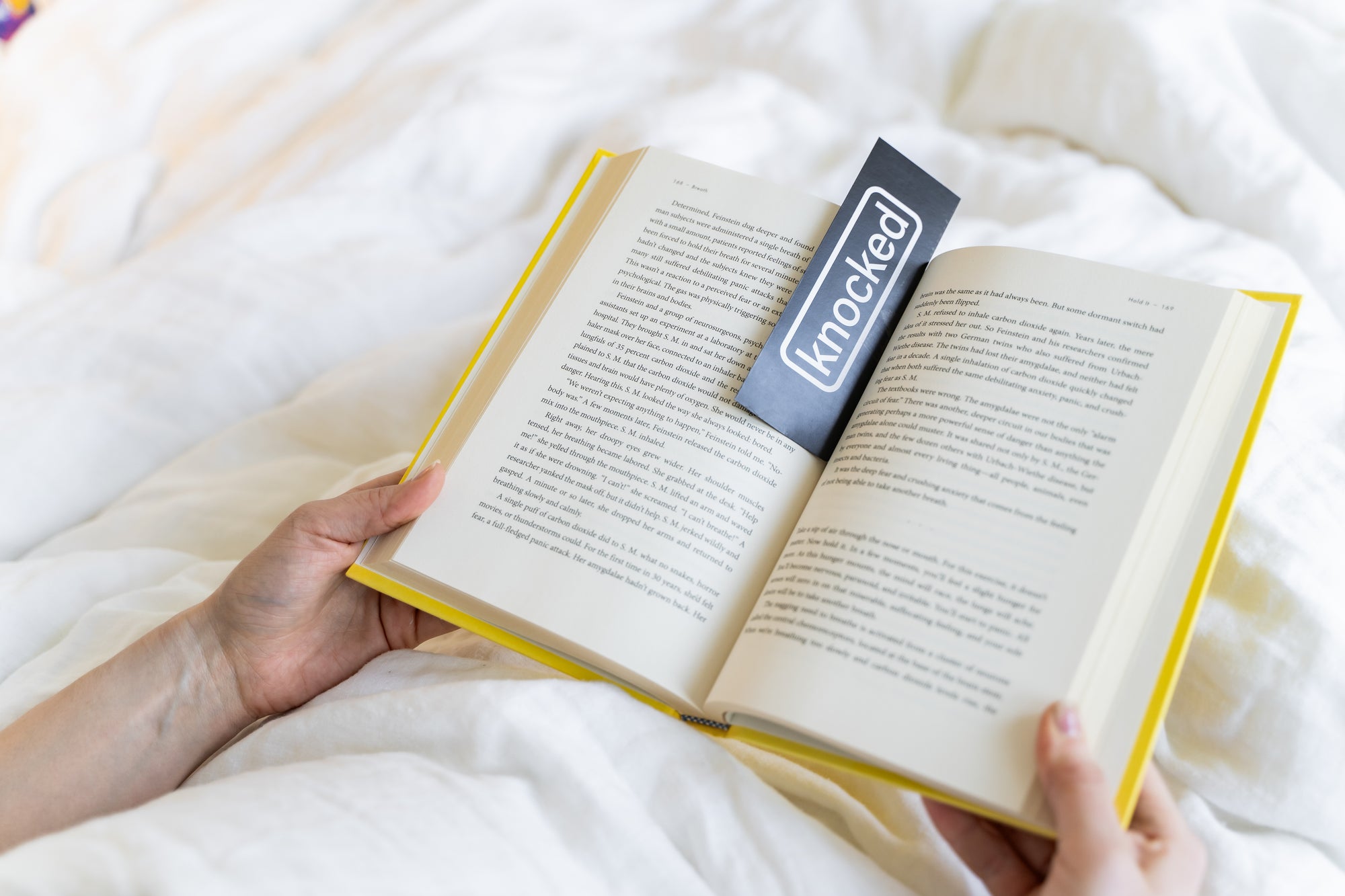 reading a book in bed using a Knocked bookmark