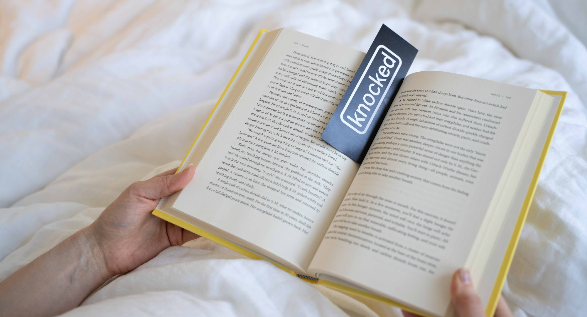 Reading a book about sleep in bed with a Knocked Bookmark 